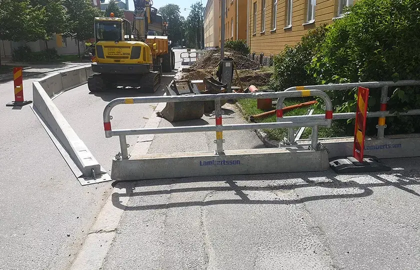 En avstängd gata omgärdas av räcken ifrån Lambertsson och innanför avspärrningen står en grävmaskin ifrån Lindeskov Gräv